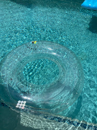 Clear inflatable ring with 'Cali Magic' branding floating in a pool.