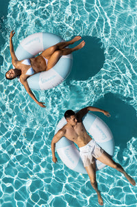 Two people floating on inflatable rings in a pool