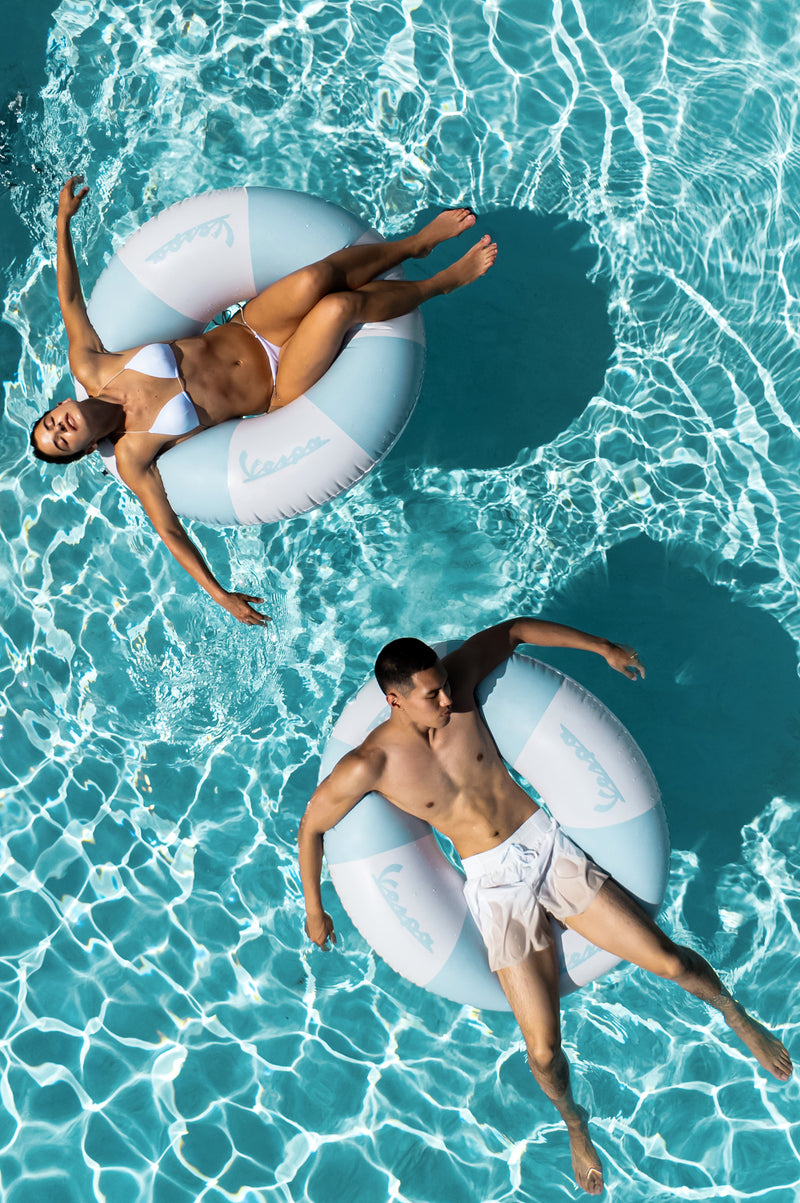 Two people floating on inflatable rings in a pool