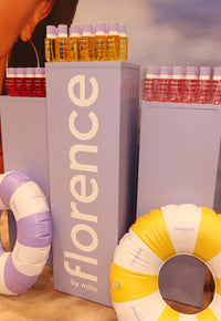 Display of 'Florence by Mills' products with colorful bottles and floaties.