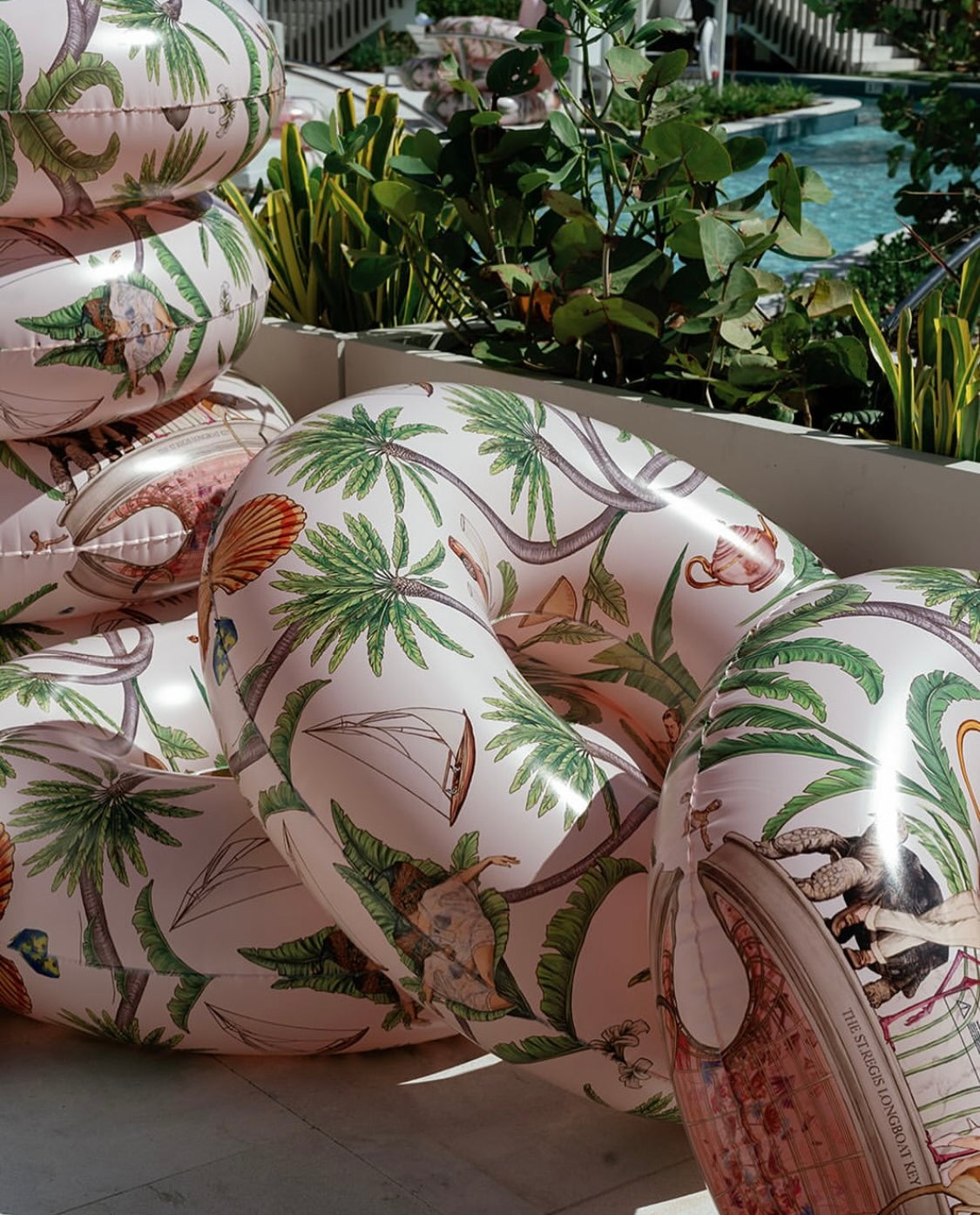 Decorative cushions with tropical patterns on a chair outdoors.