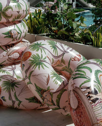 Decorative cushions with tropical patterns on a chair outdoors.