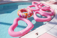 Pink heart-shaped pool floats and a colorful donut floatie in a pool.
