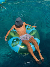 Person floating on a green inflatable ring in clear blue water