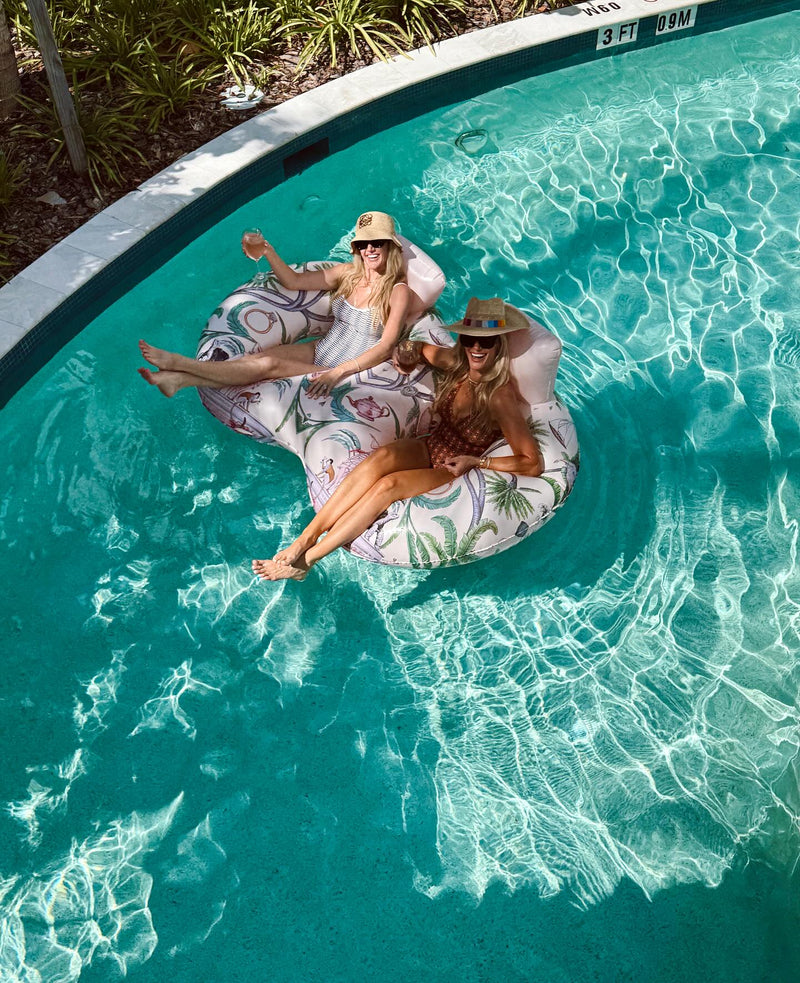 Two women relaxing on a floral inflatable ring in a pool