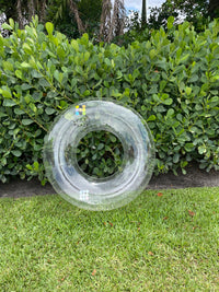 Clear plastic bottle lying on grass with green foliage in the background