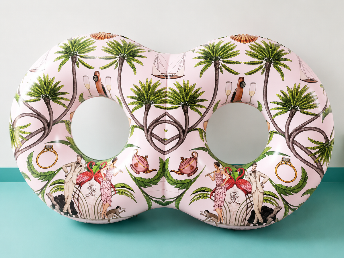 Decorative neck pillow with palm tree and beach-themed design on a teal surface.